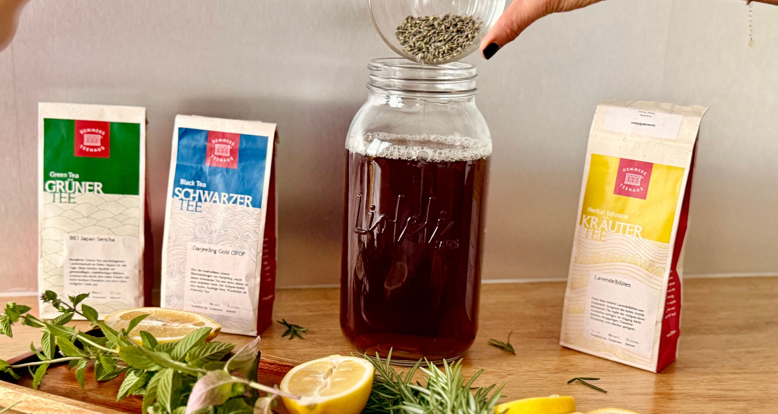 Kräuter, Zitronen im Vordergrund, dahinter Tee und Kombucha