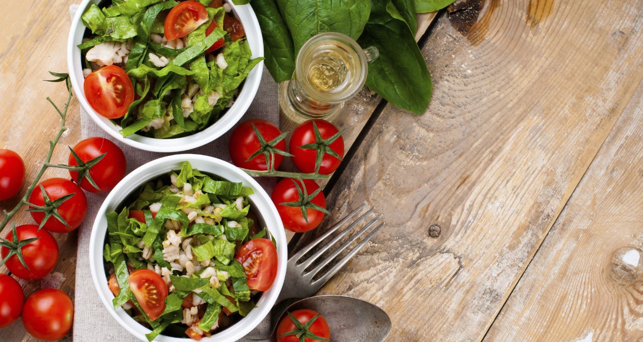 Salat in zwei Schüsseln angerichtet mit Grünerm Salat, Gerste, Tomaten von oben fotografiert