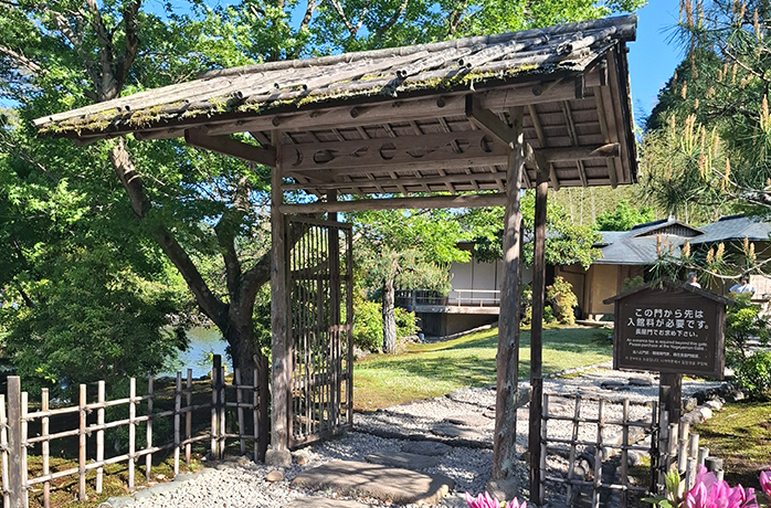 Traditionelles Eingangstor aus Holz mit Moosdach vor einem japanischen Teegarten im Grünen