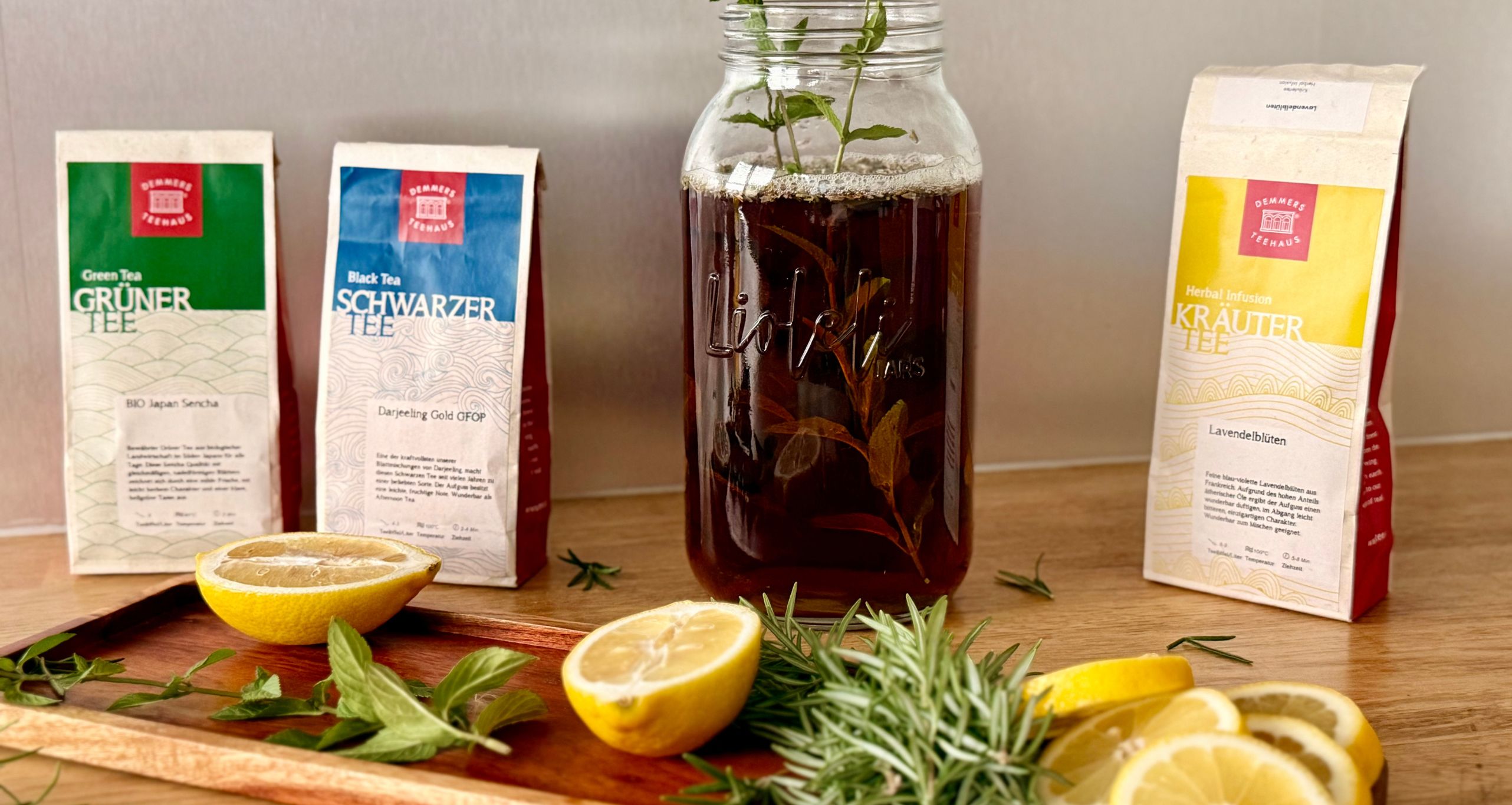 Kräuter, Zitronen im Vordergrund, dahinter Tee und Kombucha