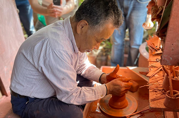 Japanischer Keramiker fertigt auf der Töpferscheibe eine traditionelle Kyusu-Teekanne mit Seitengriff Japanischer Keramiker fertigt auf der Töpferscheibe eine traditionelle Kyusu-Teekanne mit Seitengriff