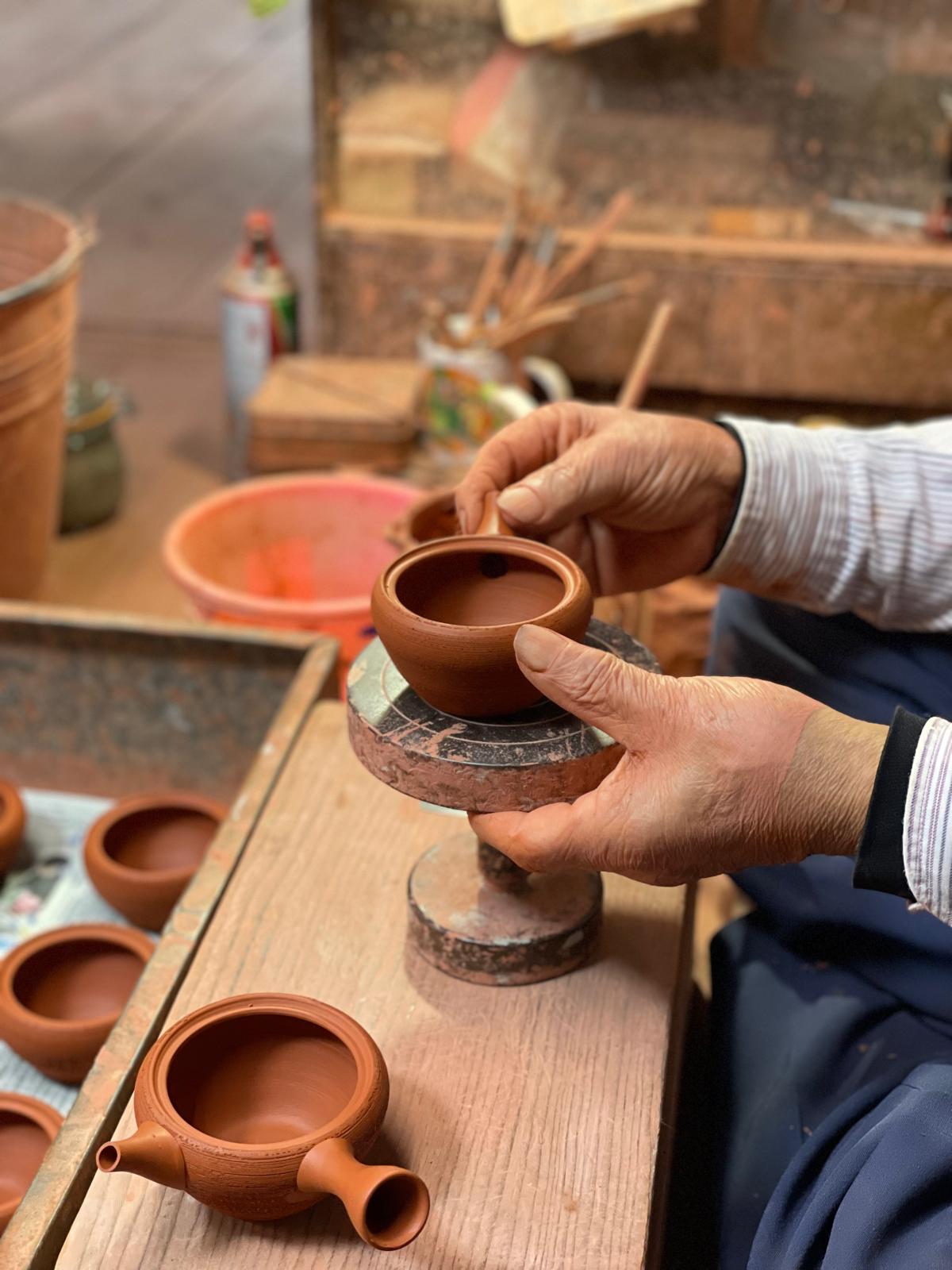 Japanischer Keramiker hält eine handgefertigte Kyusu-Kanne aus rotem Ton