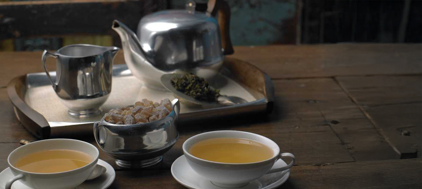 Servierter Tee mit Teekanne, zwei Tassen und Zucker auf Tablett bei Verkostung