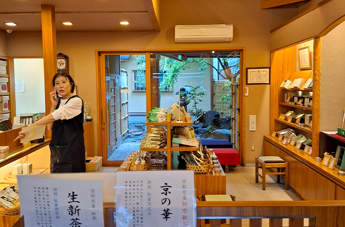 nnenansicht eines traditionellen japanischen Teegeschäfts mit Teeregalen, Verkäuferin und Blick in den grünen Innenhof