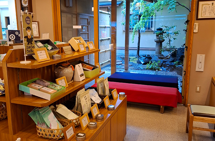 Innenansicht eines traditionellen japanischen Teegeschäfts mit Teeregalen und Blick in den grünen Innenhof
