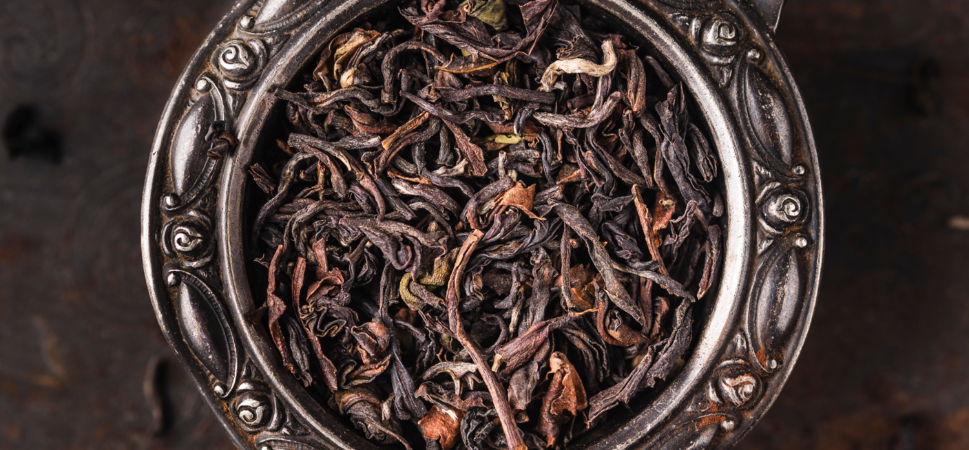 Loser Schwarzer Tee BIO Darjeeling SF Risheehat FTGFOP Kakra Musk mit rot-goldenen Blattspitzen auf goldenem Teller