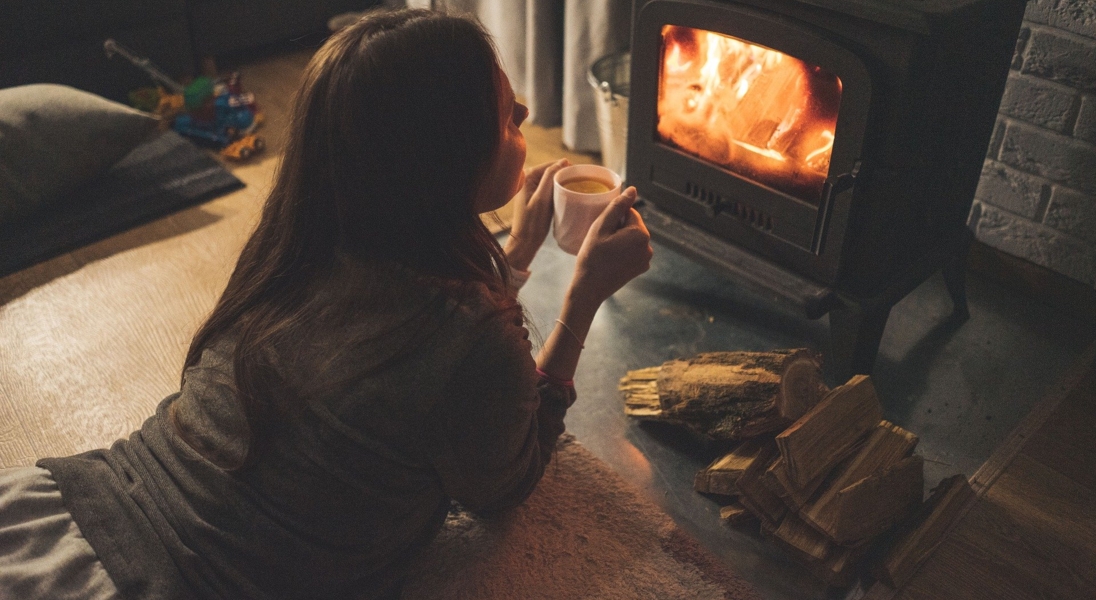 Frau trinkt eine Tasse Tee vor dem Kamin