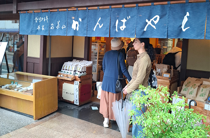 Eingang des ältesten Teefachgeschäfts Japans in Uji mit blauen noren-Vorhängen und Kund:innen beim Eintreten